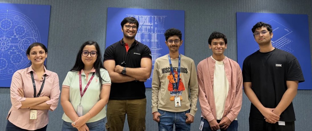 Arush with colleagues at IBM Research India, standing in front of blue quantum-chip blueprint panels